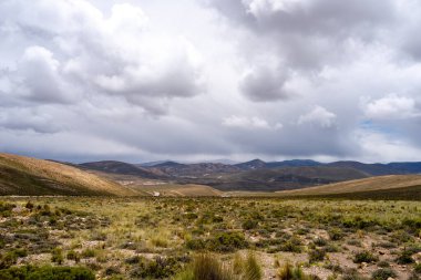 Peru 'da dramatik bir gökyüzünün altında, çölün doğal güzelliğini ve etrafındaki dağları gösteren uçsuz bucaksız, kurak bir vadi..