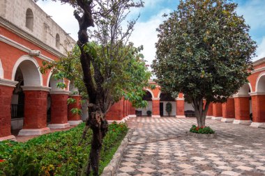 Santa Catalina Manastırı avlusu, canlı kırmızı duvarlar, ağaçlar ve çiçeklerle, sakin anlar için sakin bir alan sunar.