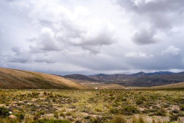 Peru 'da dramatik bir gökyüzünün altında, çölün doğal güzelliğini ve etrafındaki dağları gösteren uçsuz bucaksız, kurak bir vadi..