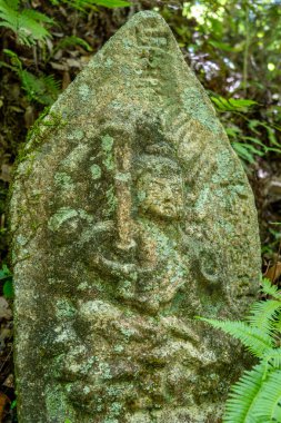 Japonya 'nın Hiroşima kentindeki Mitaki-Dera tapınak bahçesinin sessiz yeşilliklerine yerleşmiş dua eden bir keşişin huzur dolu yosun kaplı heykeli.