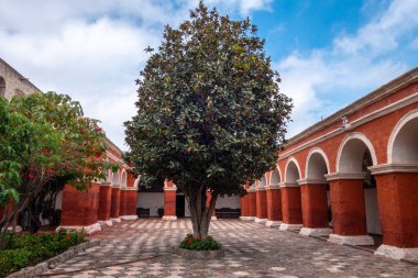 Santa Catalina Manastırı avlusu, canlı kırmızı duvarlar, ağaçlar ve çiçeklerle, sakin anlar için sakin bir alan sunar.