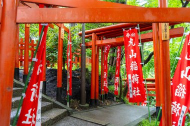 Japonya 'nın Kamakura kentindeki Tsurugaoka Hachiman-gu türbesi içine yerleştirilmiş Maruyama Inari Tapınağı' na giden yol parlak kırmızı torii kapıları ve sancaklarla çevrilidir.