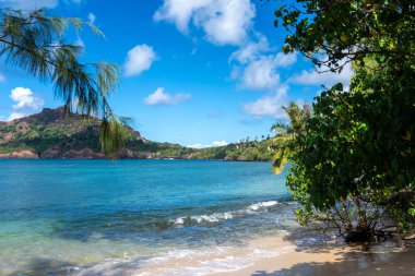 Altın kum, kristal berrak sular ve yemyeşil palmiye ağaçları yeşil volkanik dağlarla çevrili, Nuku Hiva, Fransız Polinezyası 'ndaki uzak Anaho Körfezi boyunca uzanır.