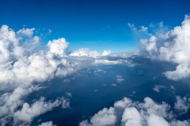 Görkemli beyaz bulutlar derin mavi Pasifik Okyanusu 'nun üzerinde yüzerler, Fransız Polinezyası üzerinde uçan bir uçaktan yakalanırlar. Nefes kesici yüksek irtifa perspektifi