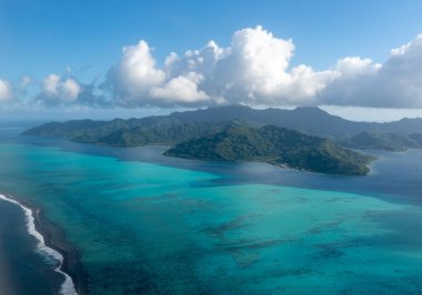 Fransız Polinezyası 'ndaki Tahaa adası, yukarıdan bakıldığında turkuaz bir göl, mercan resifi ve yemyeşil dağları ortaya çıkarır. Canlı okyanus renkleri koyu mavi Pasifik ile tezat oluşturuyor.
