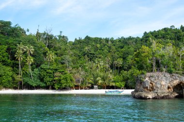 Sulawesi, Endonezya 'daki güzel Togian takımadasının bir parçası olan Waleakodi Adası' ndaki Lia plajının beyaz kumlarında renkli bir pirogue bulunur.