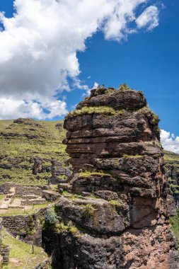 Waqrapukara 'nın antik taş duvarları ve terasları çevreleyen yeşil dağlarla harmanlanarak, İnka mühendisliğini bu uzak And arazisinde parlak bir gökyüzünün altında vurguluyor.