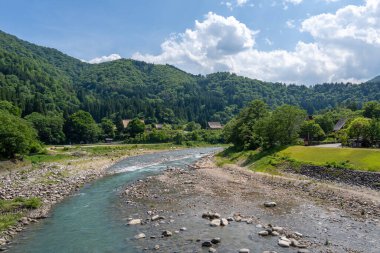 Sho Nehri, ormanlık dağlar ve huzurlu bir yaz manzarasında geleneksel sazdan evler ile çevrili Shirakawa-go 'da usulca esiyor.
