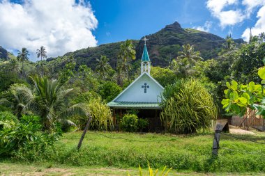 Yeşil çatısı ve beyaz çan kulesi olan büyüleyici bir kilise Anaho Körfezi, Nuku Hiva, Fransız Polinezyası 'ndaki tropikal bitki örtüsü arasında huzurlu bir ortam sunuyor.