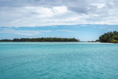 Bora Bora Adası 'nı çevreleyen küçük adaların panoramik görüntüsü, turkuaz sular ve gökyüzünde dramatik bulutlar