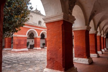 Santa Catalina Manastırı avlusu, canlı kırmızı duvarlar, ağaçlar ve çiçeklerle, sakin anlar için sakin bir alan sunar.