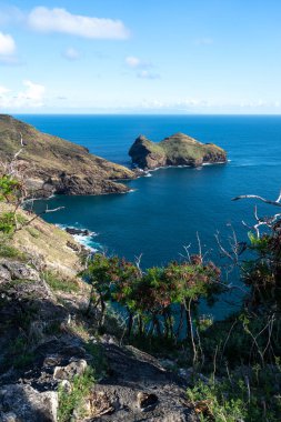 Marquesas Adaları 'ndaki Nuku Hiva' daki Taiohae Körfezi 'nin engebeli uçurumları parlak bir gökyüzünün altından çıkan küçük kayalık adalarla derin mavi Pasifik Okyanusu' na düşer. Fransız Polinezyası
