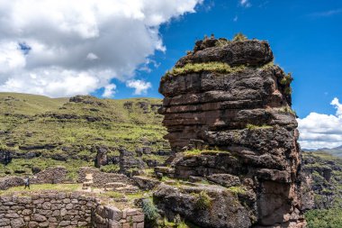 Waqrapukara 'nın antik taş duvarları ve terasları çevreleyen yeşil dağlarla harmanlanarak, İnka mühendisliğini bu uzak And arazisinde parlak bir gökyüzünün altında vurguluyor.