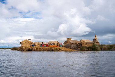 Peru, Titicaca Gölü 'ndeki yüzen Uros Titino adası, parlak bir gökyüzünün altında derin mavi sularla çevrili kamış evleri, demirlemiş tekneler ve yemyeşil bitki örtüsüne sahiptir.