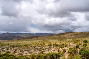 Peru 'da dramatik bir gökyüzünün altında, çölün doğal güzelliğini ve etrafındaki dağları gösteren uçsuz bucaksız, kurak bir vadi..