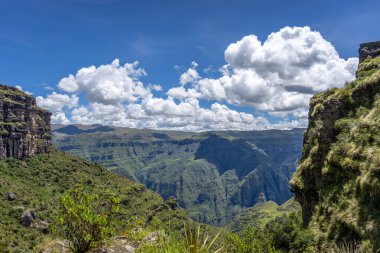 Waqrapukara arkeolojik alanını çevreleyen yeşil dağ tepeleri ve sarp kayalıklar, And 'ın berrak mavi gökyüzü altında nefes kesici panoramik manzaralar sunuyor.