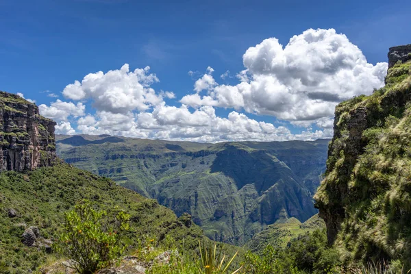 Waqrapukara arkeolojik alanını çevreleyen yeşil dağ tepeleri ve sarp kayalıklar, And 'ın berrak mavi gökyüzü altında nefes kesici panoramik manzaralar sunuyor.