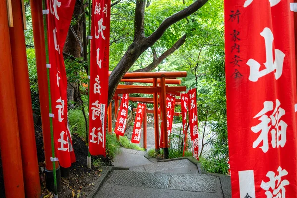 Japonya 'nın Kamakura kentindeki Tsurugaoka Hachiman-gu türbesi içine yerleştirilmiş Maruyama Inari Tapınağı' na giden yol parlak kırmızı torii kapıları ve sancaklarla çevrilidir.