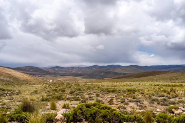 Peru 'da dramatik bir gökyüzünün altında, çölün doğal güzelliğini ve etrafındaki dağları gösteren uçsuz bucaksız, kurak bir vadi..