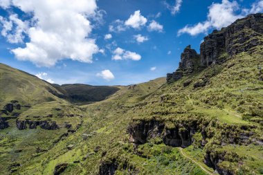 Peru 'daki Waqrapukara bölgesinde dramatik kaya oluşumları, yeşil vadiler ve dik uçurumlar yer almakta, And dağlarının parlak mavi gökyüzü altında nefes kesen manzaraları sunmaktadır.