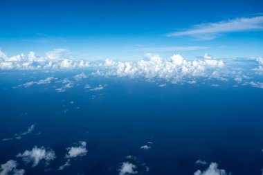 Görkemli beyaz bulutlar derin mavi Pasifik Okyanusu 'nun üzerinde yüzerler, Fransız Polinezyası üzerinde uçan bir uçaktan yakalanırlar. Nefes kesici yüksek irtifa perspektifi
