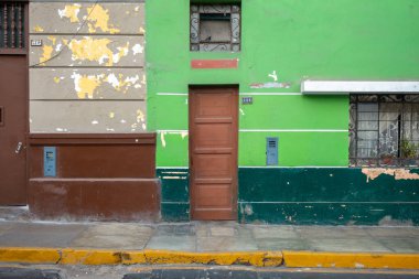 Peru, Lima 'da pencere, kapı ve bitki içeren yıpranmış görünümlü canlı yeşil bir duvar.
