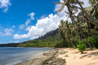 Altın kum, kristal berrak sular ve yemyeşil palmiye ağaçları yeşil volkanik dağlarla çevrili, Nuku Hiva, Fransız Polinezyası 'ndaki uzak Anaho Körfezi boyunca uzanır.
