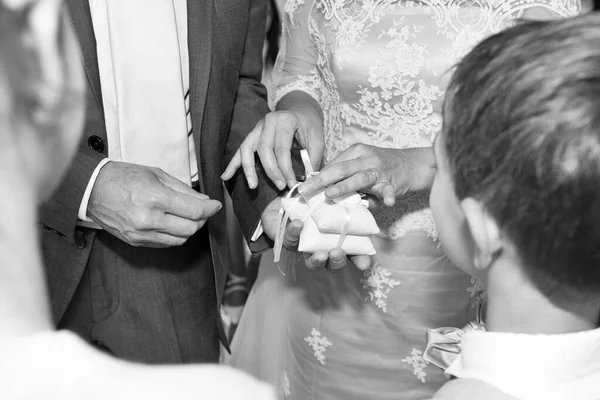 Düğün günlerinde yüzüklerini değiş tokuş eden bir çiftin fotoğrafı.