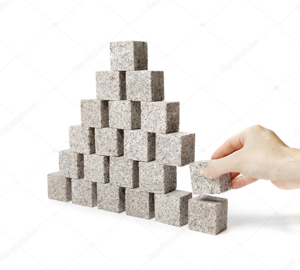 Hand removing one block of a pyramid