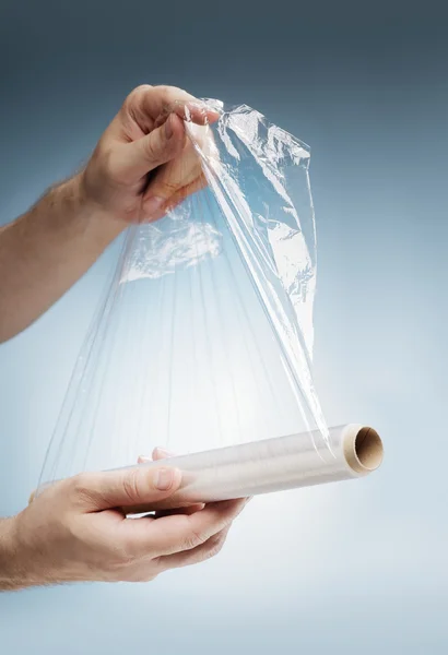 Man holding a roll of plastic film — Stock Photo, Image