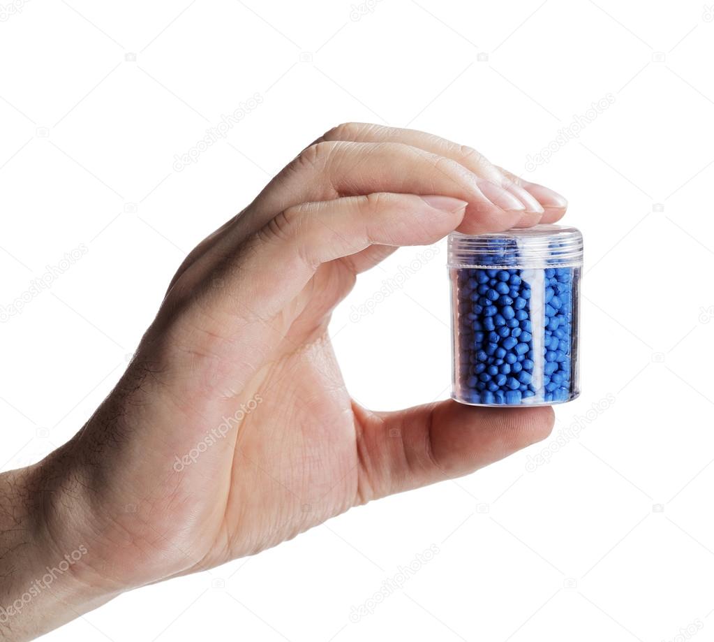 Man holding a small container with blue plastic granules
