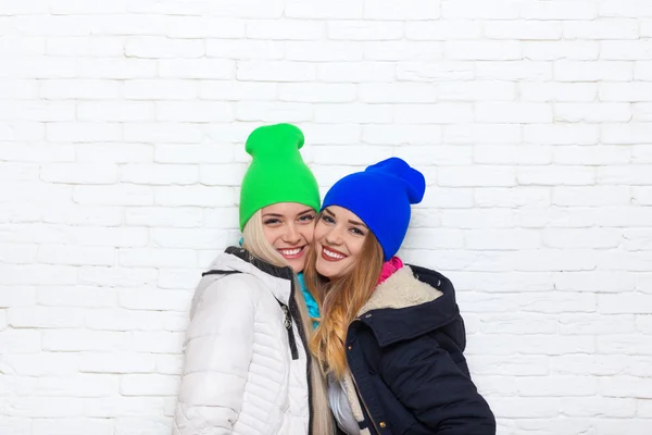 两个女孩夫妇微笑穿颜色鲜艳的帽子夹克 — 图库照片