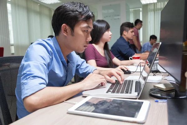 Азиатский бизнесмен сидит за рабочим столом и работает с ноутбуками — стоковое фото