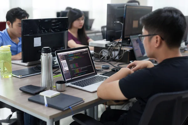 Asiatisches Outsourcing-Entwicklerteam sitzt am Schreibtisch und arbeitet am Laptop — Stockfoto