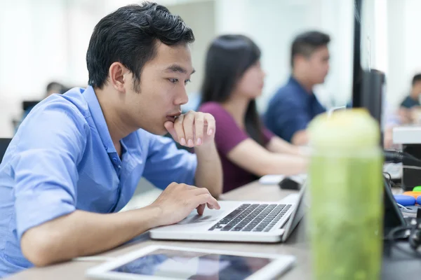 Asiatischer Geschäftsmann sitzt am Schreibtisch und arbeitet am Laptop — Stockfoto