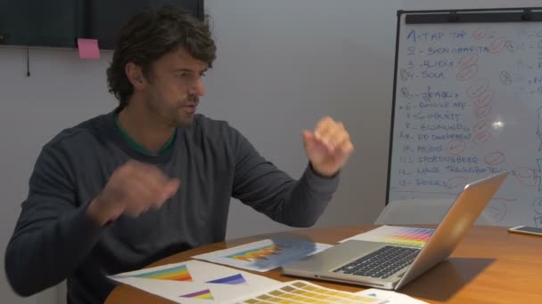 遅くまで働く男、座っているオフィスデスクのラップトップコンピュータペーパー否定的な感情 — ストック動画