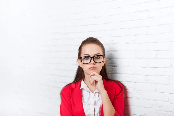 Podnikatelka seriózního červenou bundu brýle držet bradu zamyšlení — Stock fotografie