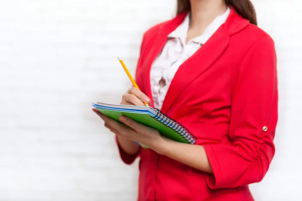 Kobieta interesu przytrzymaj notebook ołówek pisać wear czerwona kurtka — Zdjęcie stockowe