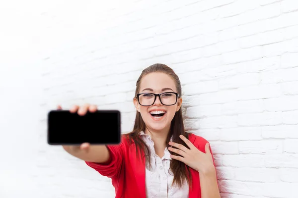 Geschäftsfrau zeigt Handy-Bildschirm mit leerem Kopierraum trägt rote Jacke Brille glückliches Lächeln — Stockfoto