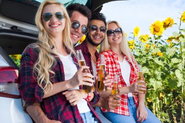 Arkadaşlar araba bagajı açık kırsal oturan bira şişeleri içme