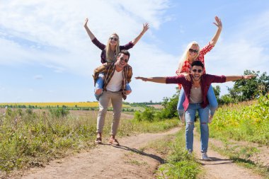 İki erkek kız arkadaş piggyback neşeli çift genç arkadaşlar sürmek