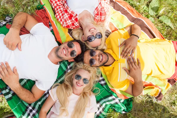 Happy people group young friends lying down on picnic blanket outdoor