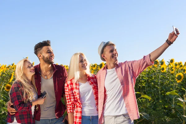 Amici scattare foto selfie smart phone campagna girasoli campo — Foto Stock