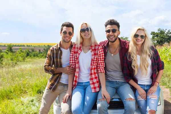 Přátelé sedící na auto venkovní krajinu lidi úsměv — Stock fotografie