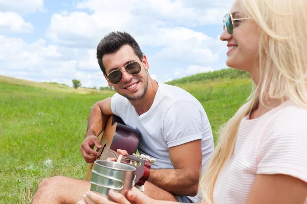 Hombre joven tocando la guitarra a su pareja chica día de verano —  Fotos de Stock