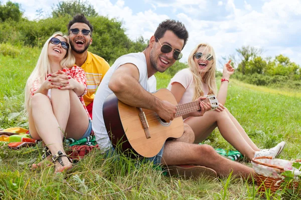 Giovani ascoltando ragazzo suonare chitarra gruppo amici estate giorno — Foto Stock