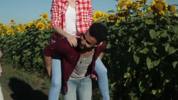 Dwóch mężczyzn dziewczyn piggyback jeździ wesoły para młodych przyjaciół lato słoneczny dzień młodzieży Grupa countryside droga — Wideo stockowe
