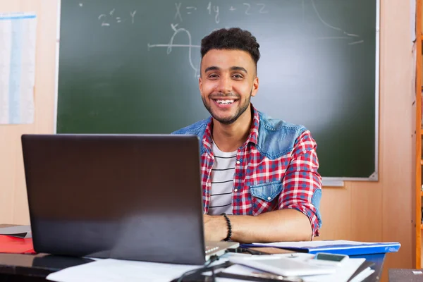 Hombre hispano usando computadora portátil, estudiante en el aula universitaria en el escritorio sobre pizarra —  Fotos de Stock