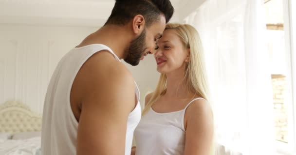 Пара любові обіймає посмішку стоячи обличчям до обличчя мікс гонка чоловік жінка обіймає ранкову спальню — стокове відео