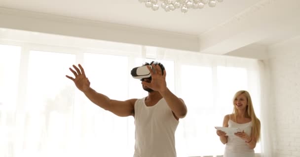 Homme utilisant des lunettes de réalité virtuelle femme tenant ordinateur tablette numérique concept de technologie 3d, mélanger course couple maison jouer jeu vidéo sourire — Video